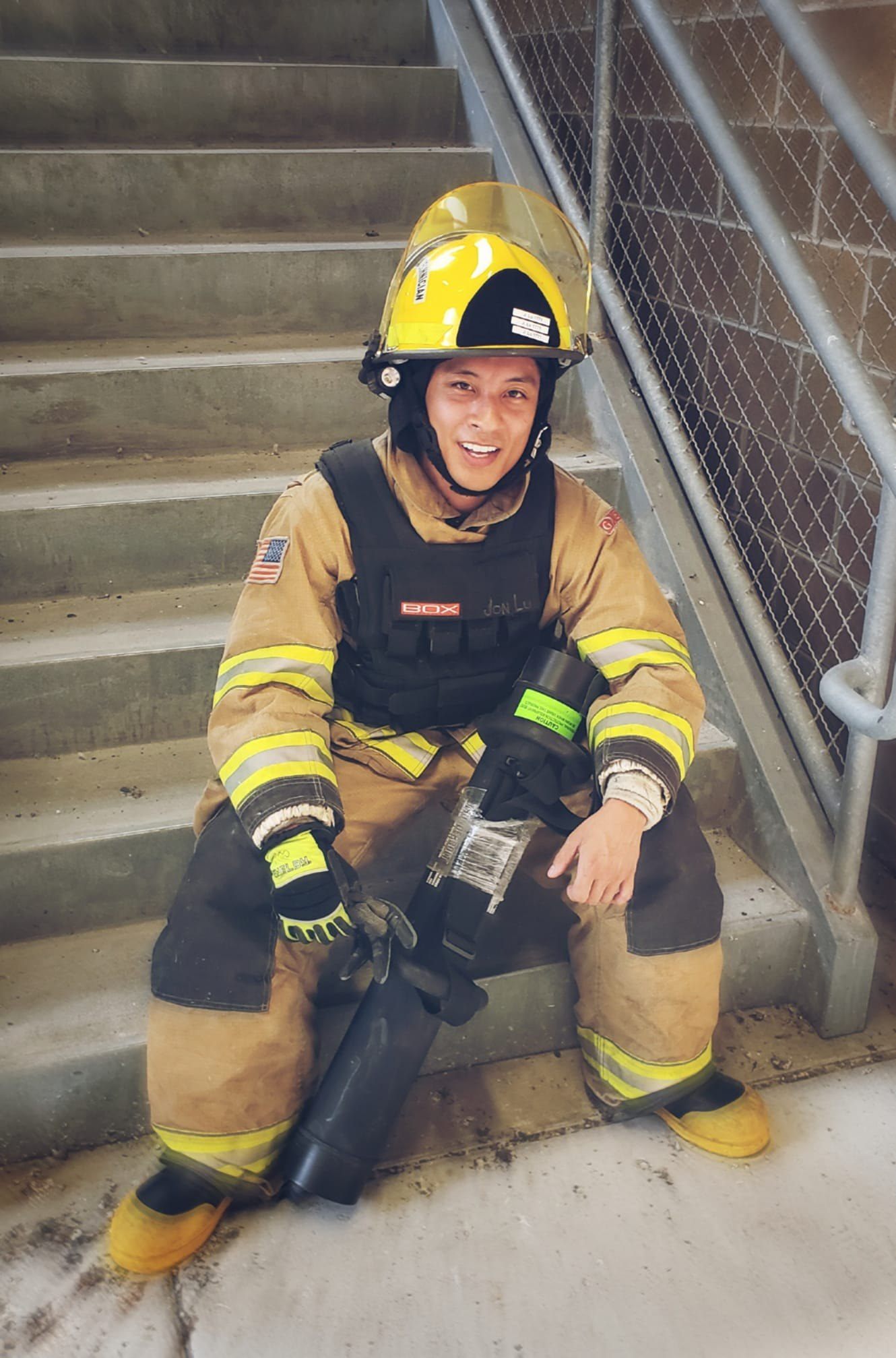 Jonathan Lu seated on stairs in firefighter turnout gear